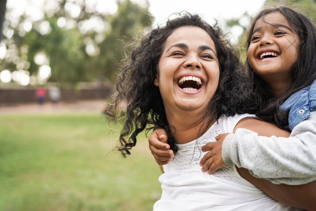 Happy mother and daughter having fun outdoor at a park. Enjoying a being playful with her child after being helped by the BodyFree weight loss surgery program.