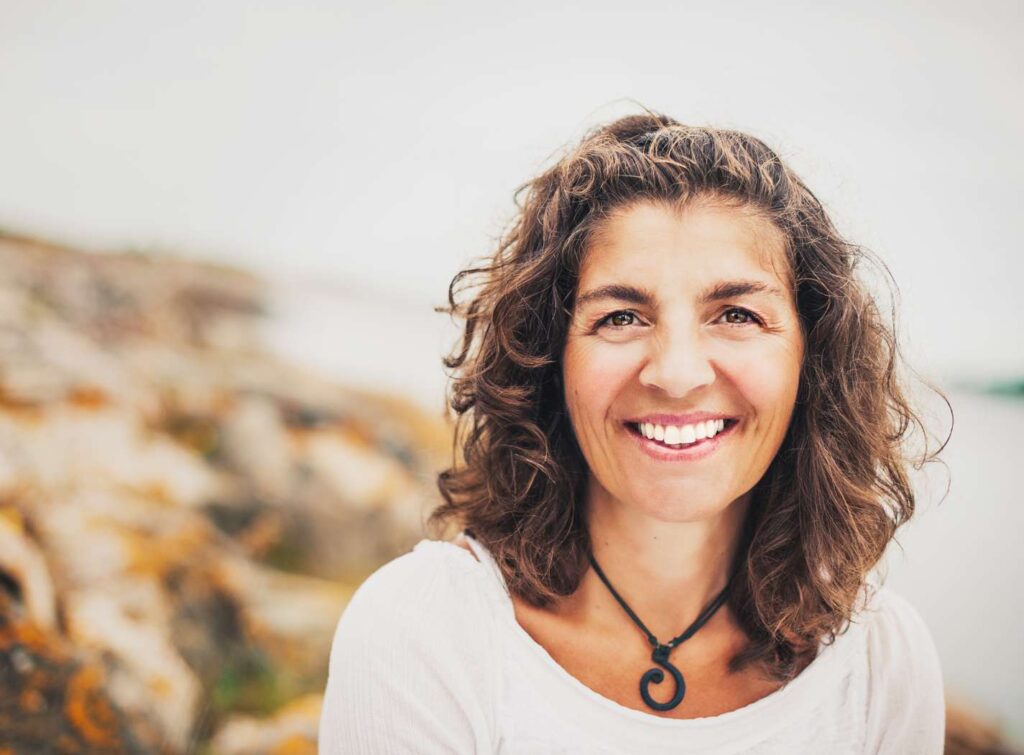 Smiling woman with curly hair outdoors.